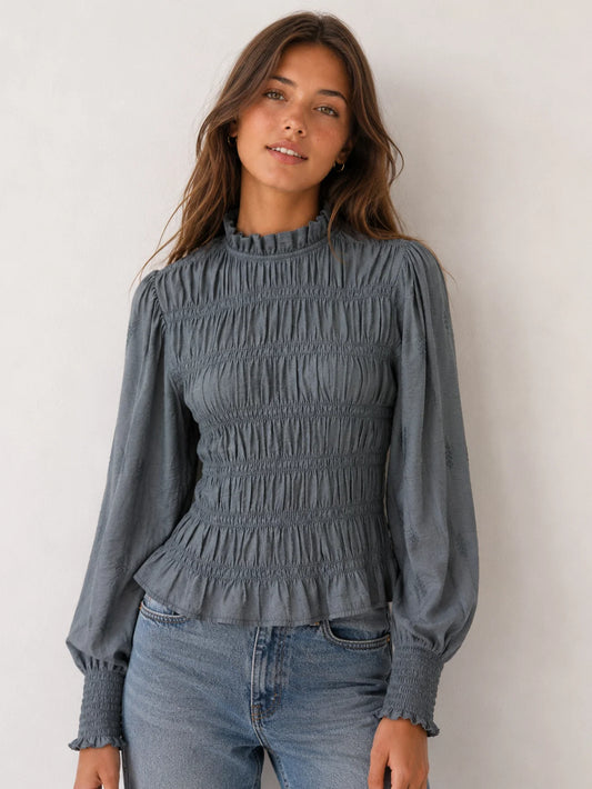 Blusa de manga larga gris con nido de abeja y cuello subido combinada con vaqueros modelo