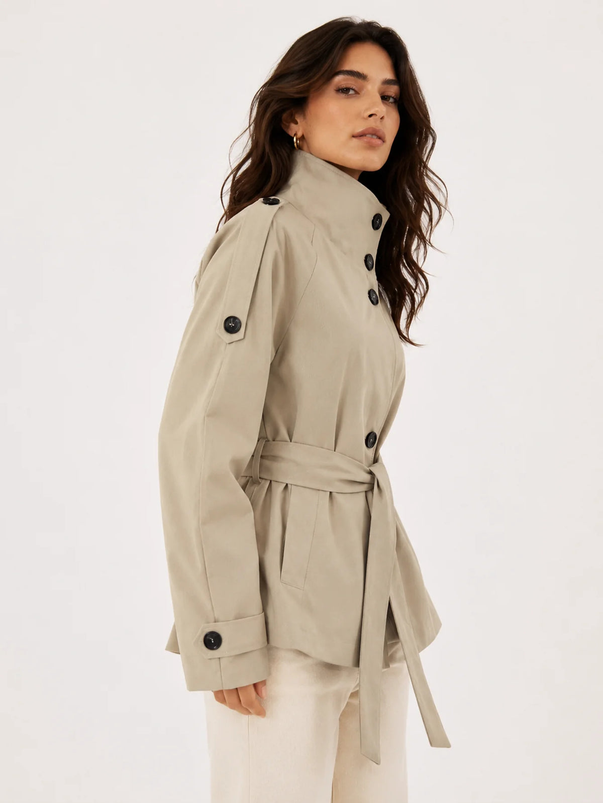 Detalle de chaqueta estilo gabardina con cinturón anudado y bolsillos laterales