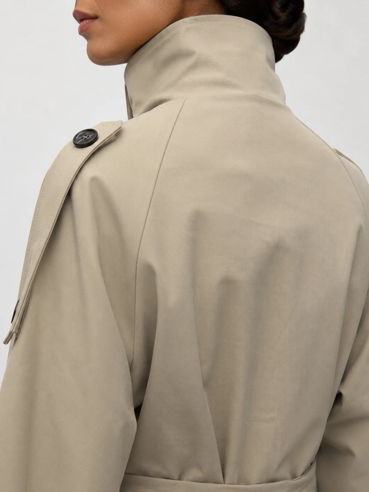 Vista trasera de chaqueta corta de estilo gabardina con cinturón y detalle en puños