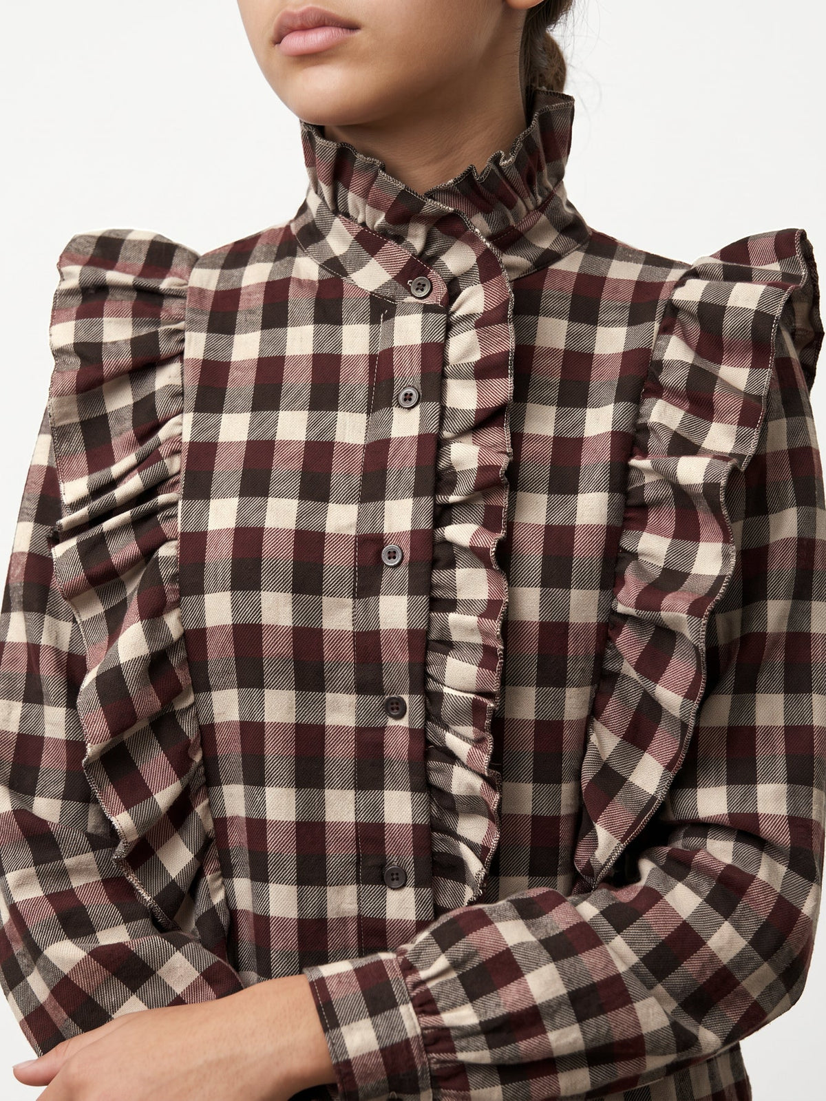 Detalle de volantes delanteros y cuello alto en blusa de cuadros de manga larga