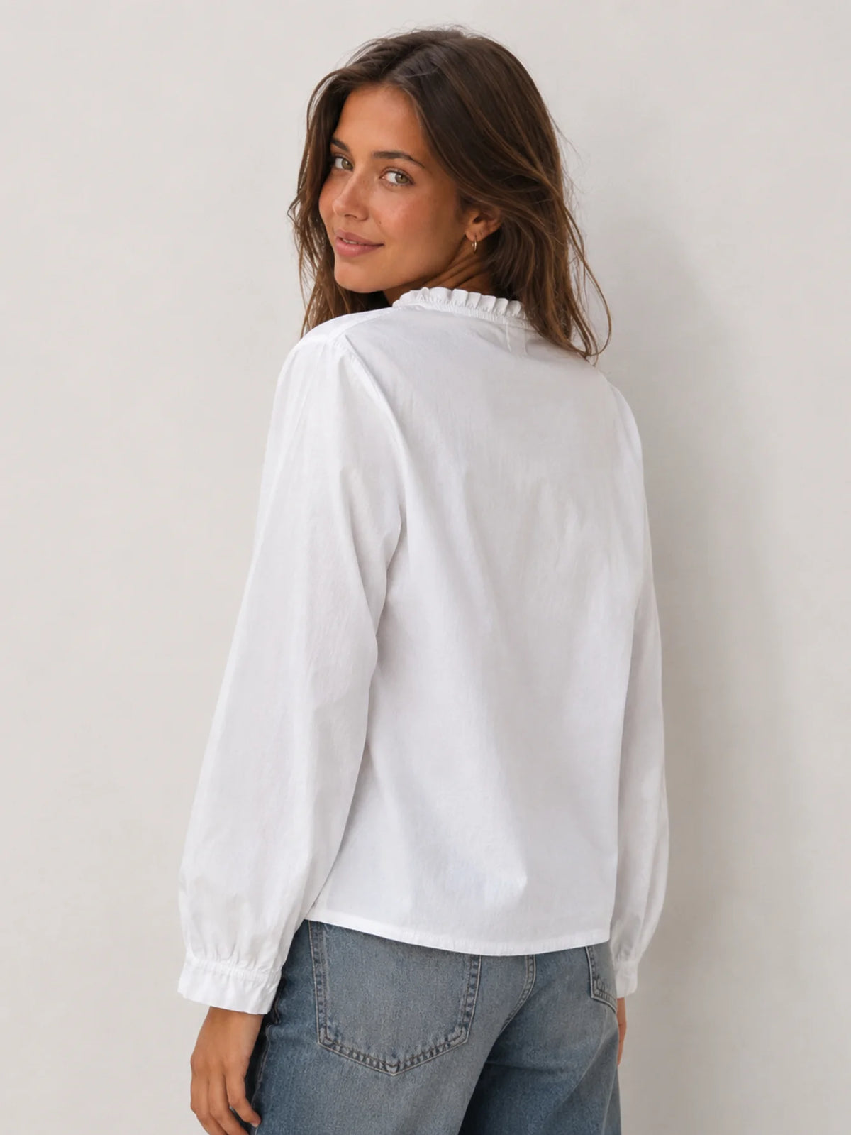 Vista lateral y de espalda de la blusa blanca de manga larga con tejido fluido