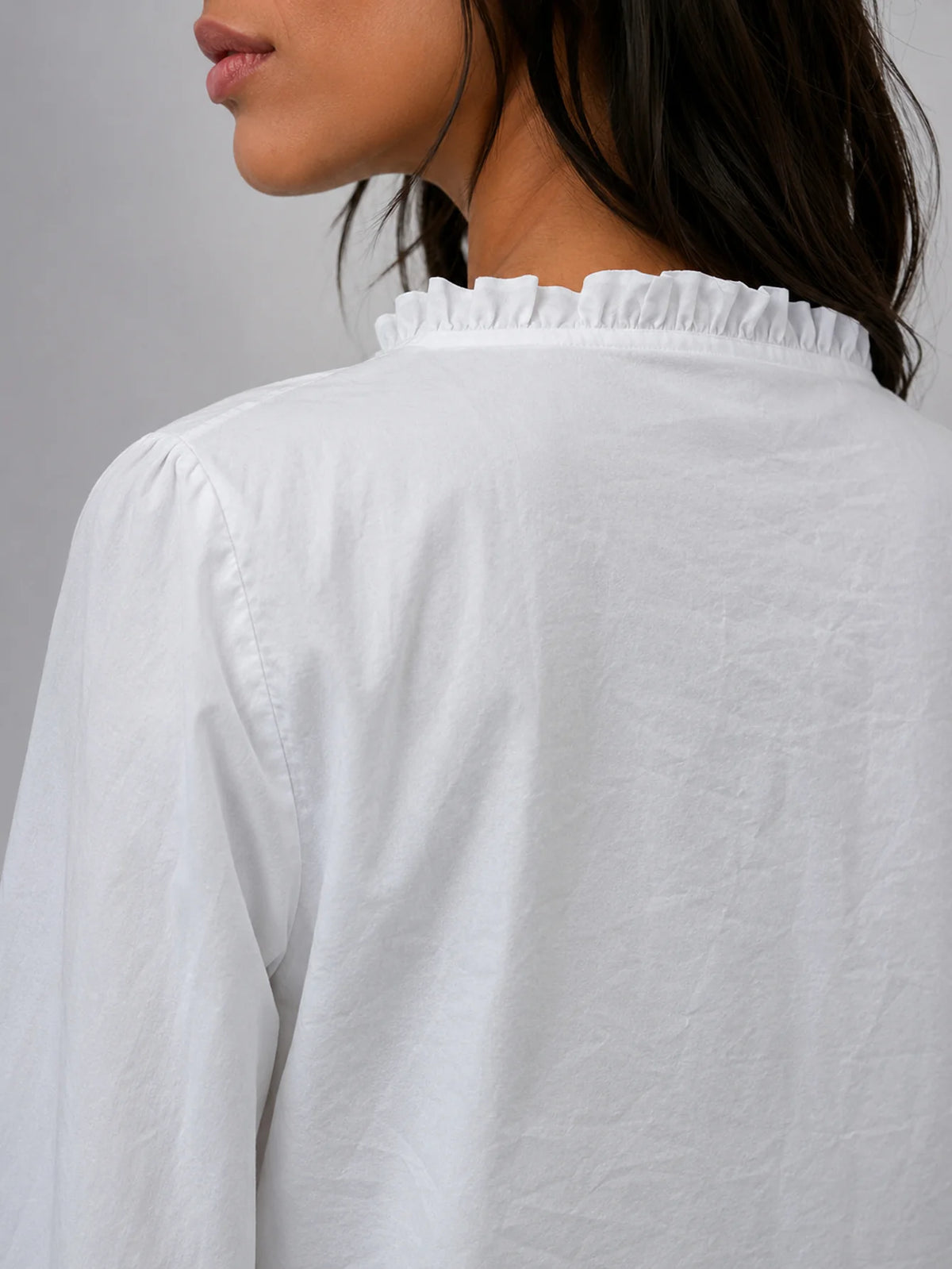 Vista lateral y de espalda de la blusa blanca de manga larga con tejido fluido
