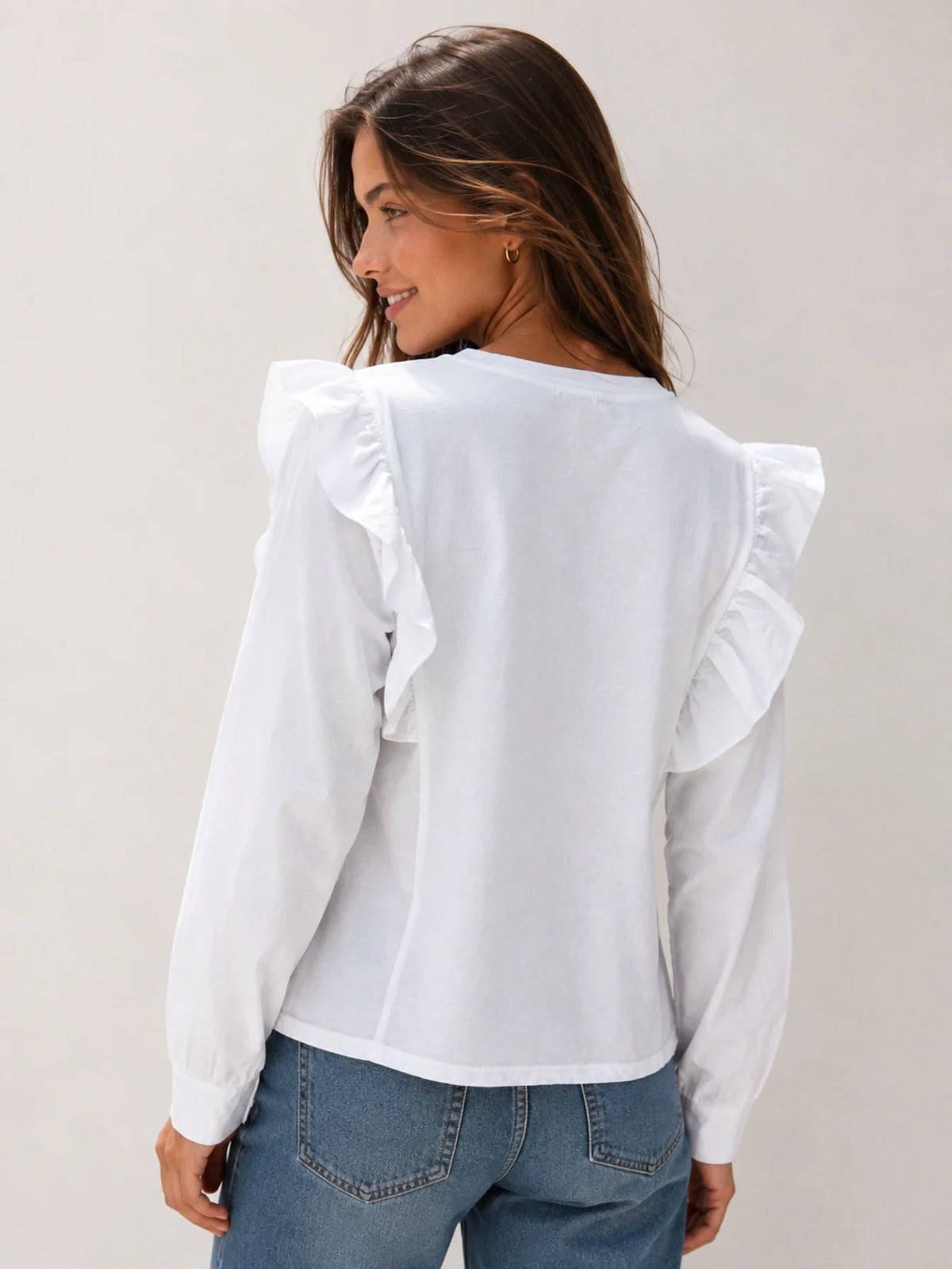 Mujer vistiendo camiseta blanca casual con volantes y tachuelas combinada con vaqueros