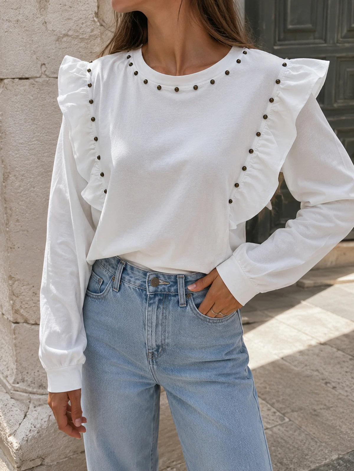 Look casual con camiseta blanca de algodón con volantes y tachuelas y pantalones vaqueros