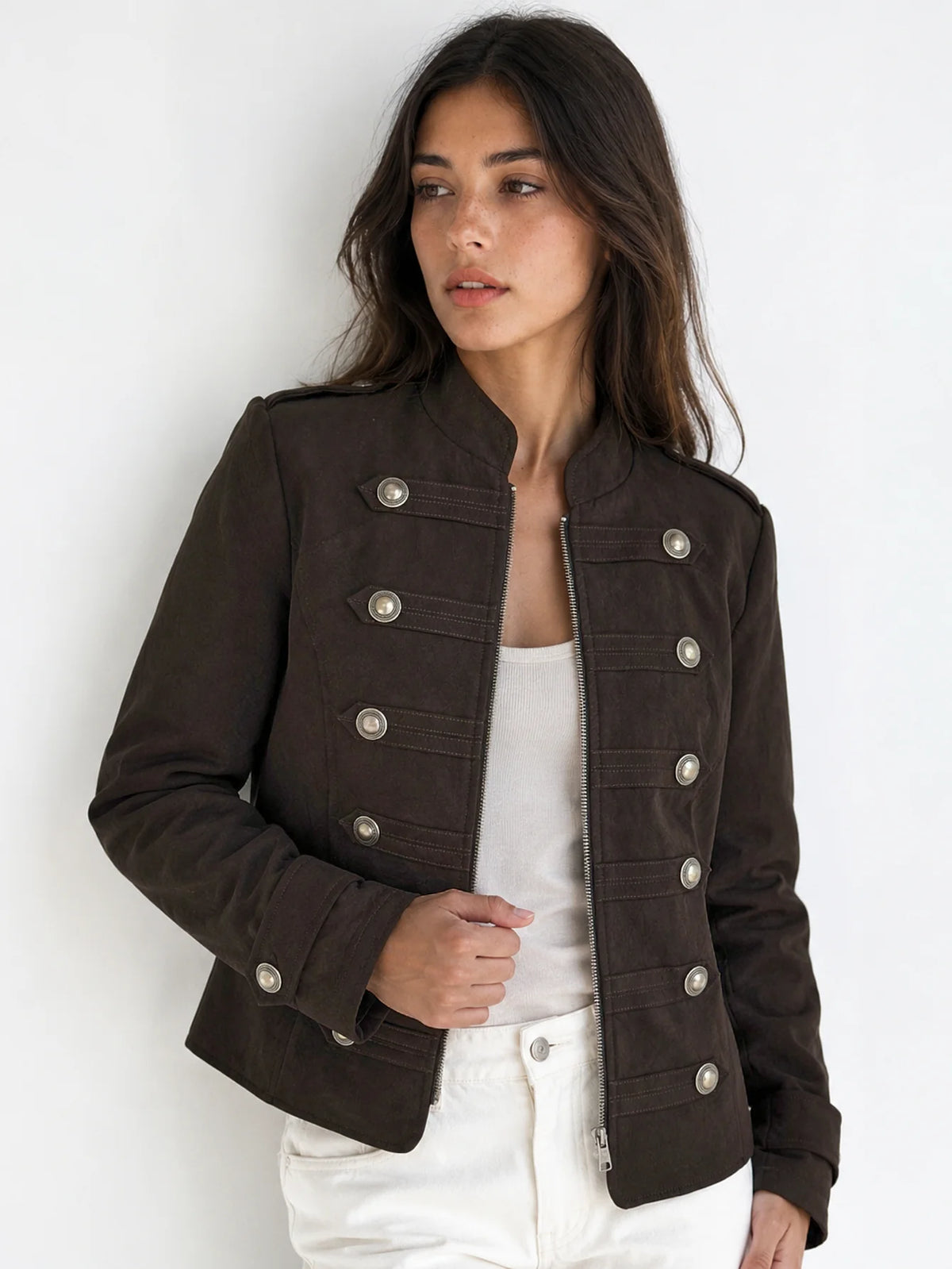 Modelo con chaqueta efecto ante marrón, cuello subido y botonadura metálica, combinada con pantalón blanco.