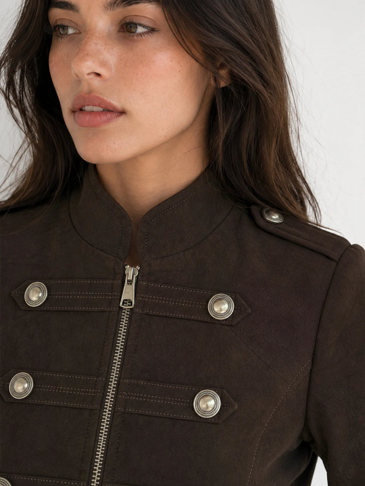 Detalle de la botonadura metálica decorativa de estilo militar en chaqueta efecto ante marrón.